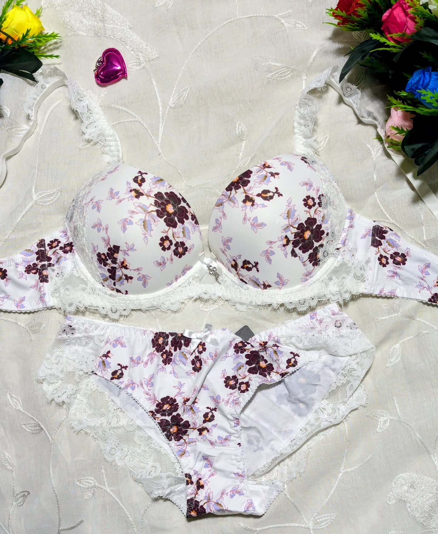 Floral lingerie set on a textured surface with flowers in the background